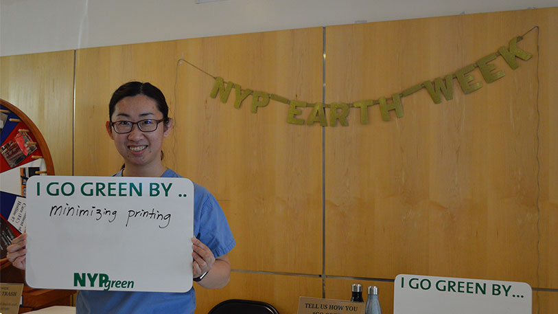 A man holding a sign that say I go green by... minimizing printing