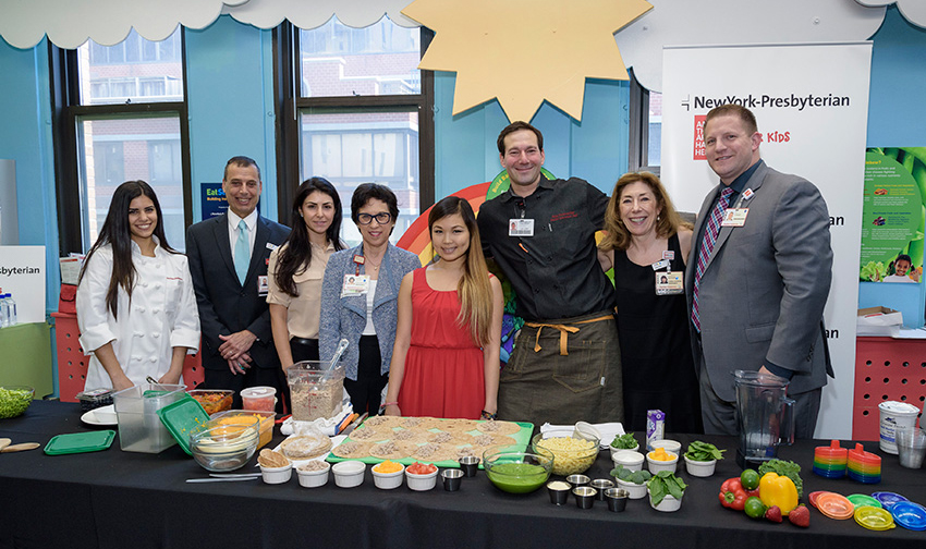 a group of people standing around a table with food on it