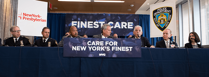 a group of people sitting at a table with a banner behind them