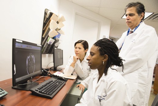 A group of doctors reviewing a brain scan on a computer screen