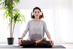 A woman sitting on the ground with her legs crossed meditating 