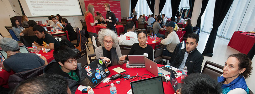 a group of people sitting at a table with laptops