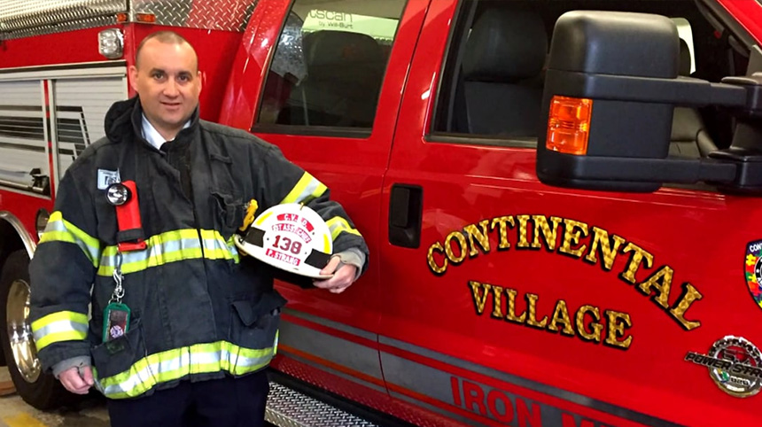 Patrick strang posing next to his fire truck in uniform