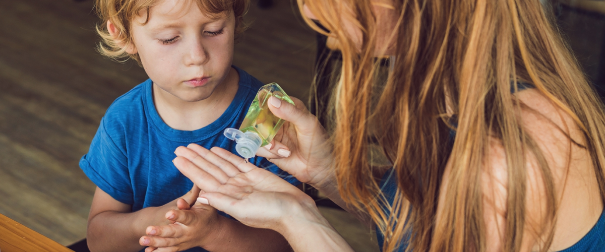 two kids putting hand sanitizer on their hands