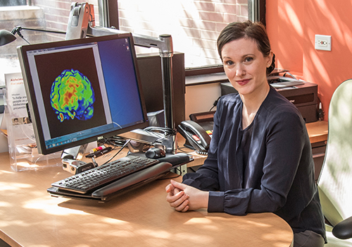 Dr. Mosconi sitting at her desk with a brain scan on her computer