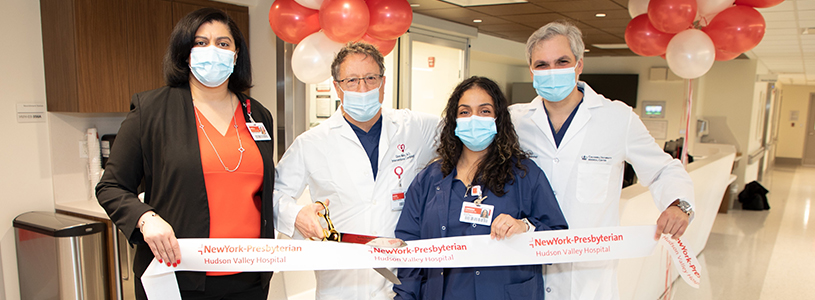 A group of people posing for a photo before cutting a ribbon