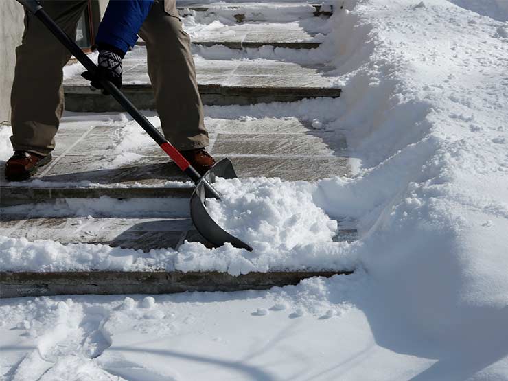 Image of a shovel moving snow on a sidewalk, to avoid back pain.