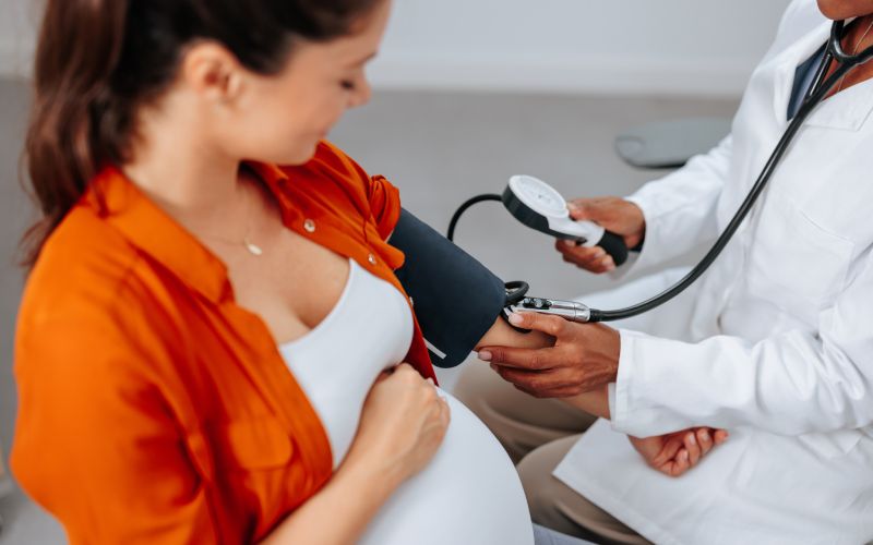 A pregnant woman having her blood pressure measured by a medical professional.