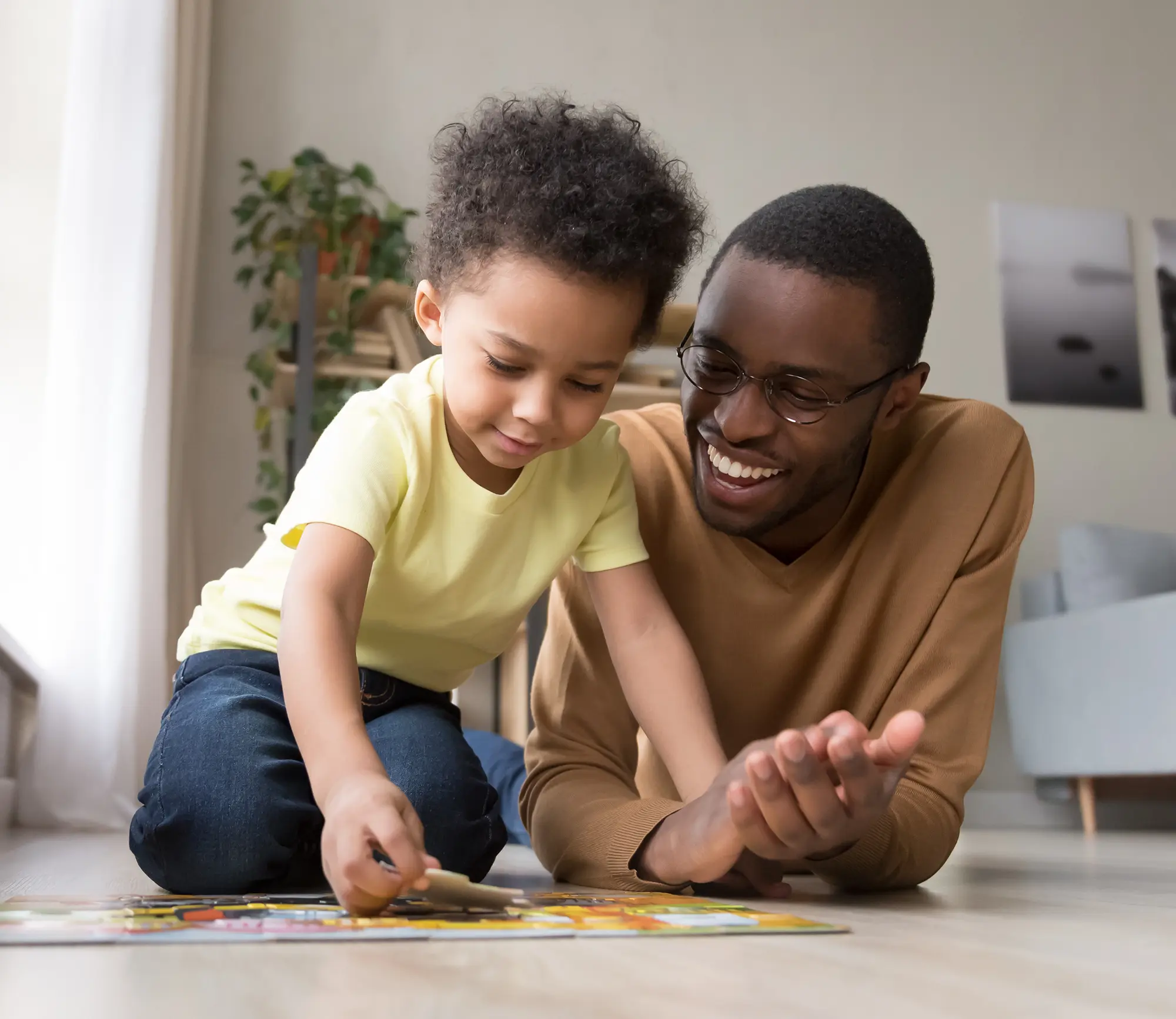 African father and little son collect jigsaw puzzle at home