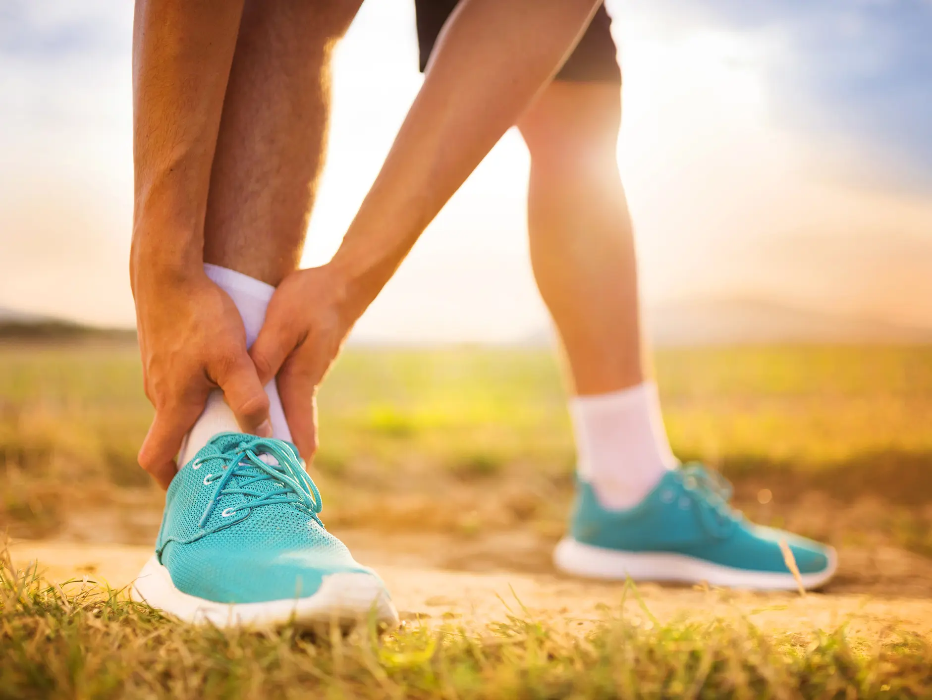 person bending down holding ankle