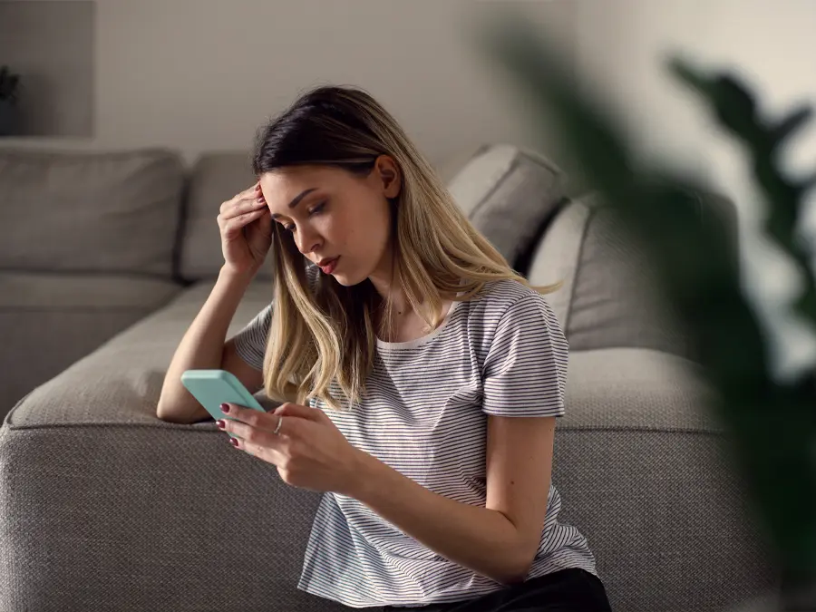 young woman looking at phone with concerned expression